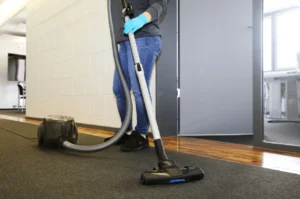 Person vacuuming carpet with canister vacuum