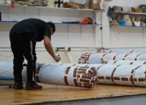 Worker wrapping rolled rugs for shipping